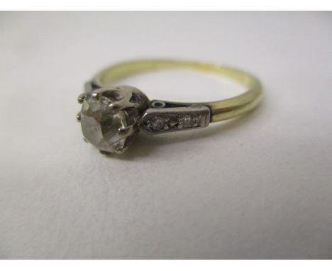 A gold and platinum coloured ring set with an oval diamond, approximately 0.65ct with four diamonds to the shoulders, stamped