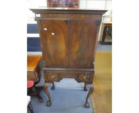 A reproduction mahogany drinks cabinet having a dental moulded cornice, twin doors, a brushing slide, three drawers on cabrio