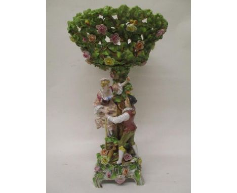 A Schierholz porcelain centrepiece encrusted with leaves and flowers, with a detachable, pierced bow, elevated by a couple, t