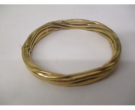 A gold coloured metal bangle with rope twist style ornament, stamped 9kt, 22.2g total 