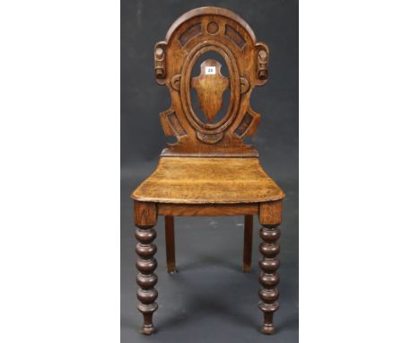 A Victorian oak hall chair with a carved &amp; pierced shaped back, having a hard seat, &amp; on bobbin-turned legs.