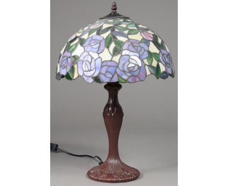 A modern Tiffany-style lamp, the leaded coloured glass domed shade decorated with pink &amp; blue roses, on bronzed compositi
