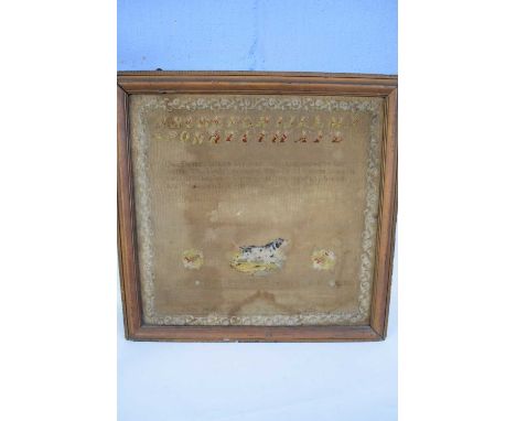 A large 19th century needlework sampler decorated with rows of letters, religious text, floral border and a central dog, sign