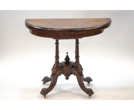 A Victorian walnut demi-lune card table with marquetry top on four column supports and ceramic casters, 71cm high x 88cm wide