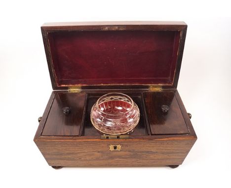 A 19th century rosewood tea caddy of sarcophagus form with ring handles, two lidded compartments and later glass mixing bowl,