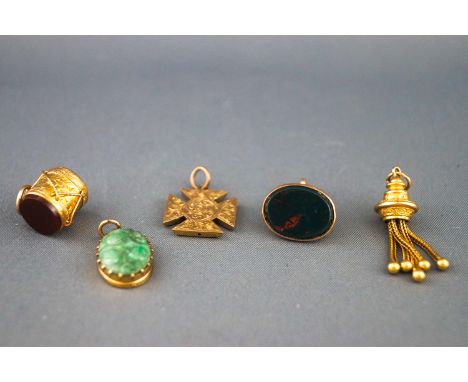 A selection of gold charms to include a bloodstone seal (uncarved), a Maltese cross, a gold tassel, a carved jade pendant and