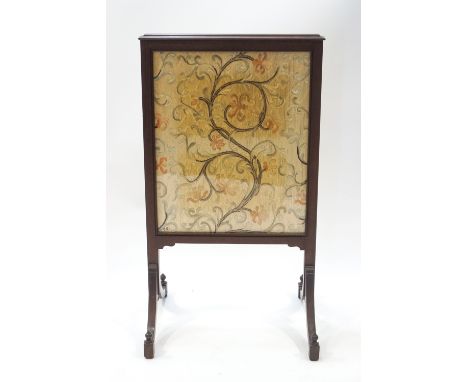 An Edwardian mahogany fire screen, silkwork panel of scrolling foliage to one side, a printed design to the other, 93cm high 