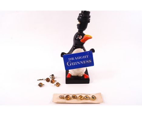 A Guinness advertising pottery table lamp, modelled as a penguin holding a 'Draught Guinness' sign, 24.5cm high, together wit