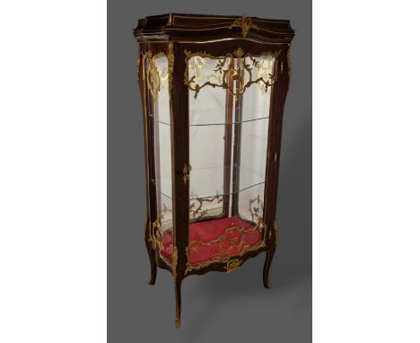 A French large Vitrine with a serpentine glazed double sided door enclosing glass shelves raised upon cabriole legs with scro