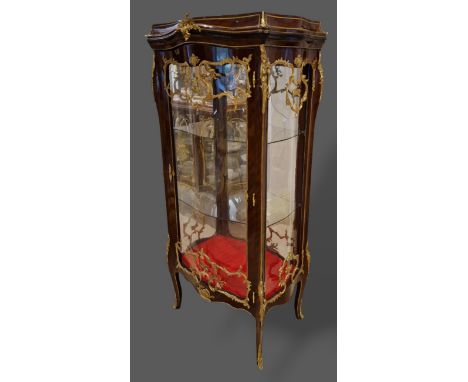 A French large Vitrine with a serpentine glazed double sided door enclosing glass shelves raised upon cabriole legs with scro