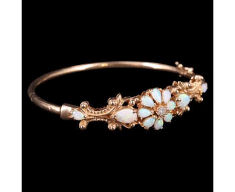 A 1980s diamond, opal and 9 ct gold fancy floral hinged bangle, faced with a flowerhead arrangement of a diamond brilliant an