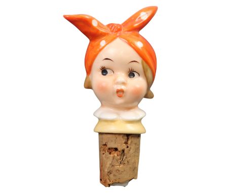 A novelty painted porcelain bottle stopper / spout, in the form of a comical girl's head wearing a tied polka-dot head scarf,