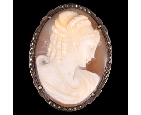A vintage shell cameo brooch, depicting the profile of a demure woman with her hair in ringlets, in a marcasite and white met