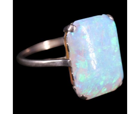 A vintage opal and precious white metal dress ring, comprising an oblong cabochon of 11 mm x 16 mm claw-set between the bifur