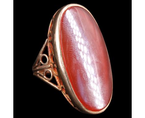 A 1970s carnelian and 9 ct gold cocktail ring, comprising an elongated oval cabochon collet-set between the tapering open-scr