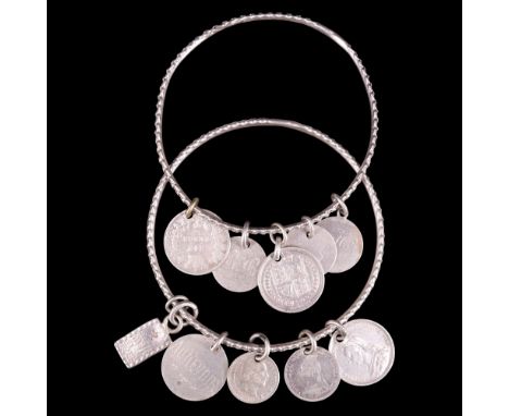 A pair of late Victorian silver charm bangles, each fine bangle cusped and facetted and carrying silver coins, one face of ea