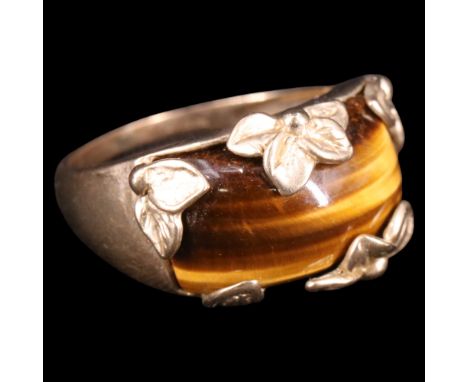 A contemporary tiger's eye and 9 ct gold floral finger ring, its contoured oblong cabochon set in a flowerhead-and-foliate ad