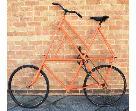 A CIRCUS BICYCLE  painted orange, with a high frame and rear foot step/rest, the wheels 61cm (24 inches) diameter, overall 15