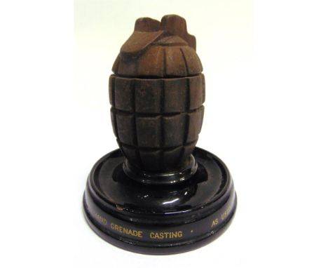 A NOVELTY INKWELL IN THE FORM OF A HAND-GRENADE complete with white ceramic liner, set to a circular black ceramic base marke