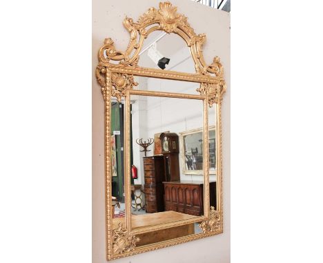 A Modern Gilt Framed Overmantel Mirror, floral swags and surmounted by a shell, 99cm by 165cm