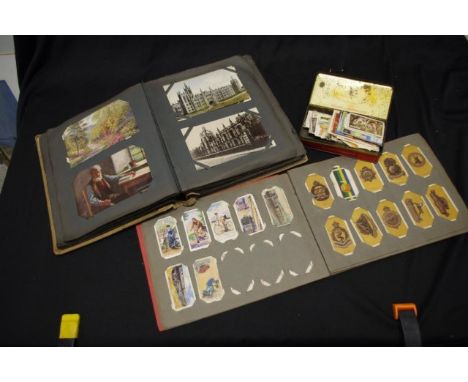 One album of mostly English vintage postcards together with one album and a tin of vintage cigarette cards
