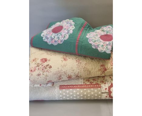 Three vintage cotton quilts or quilted bedspreads; one patchwork with floral designs and plain green to the reverse and two f