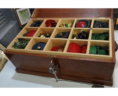Early 20th century mahogany box with metal carrying handles, the interior revealing a collection of vintage Meccano in assort