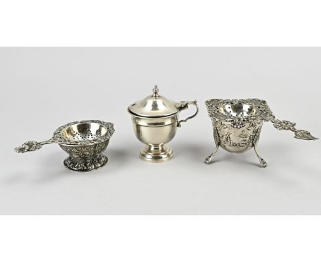 Lot of silver with 2 tea strainers on drip tray, 833/000, and a mustard pot, 925/000. The tea strainers have an openwork Bied