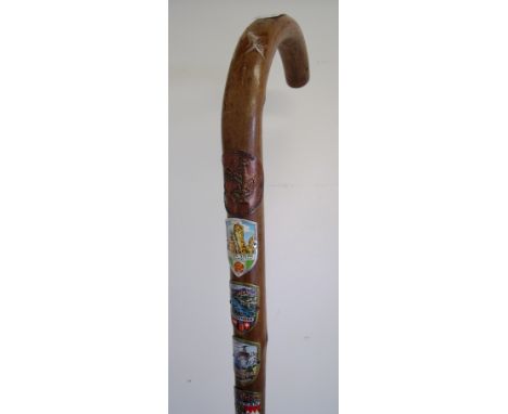 Wooden walking stick set with a large selection of various continental town badges etc 