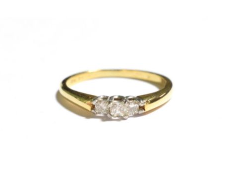 A diamond three stone ring, the graduated princess cut diamonds in white claw settings, to a yellow tapered shoulder plain po