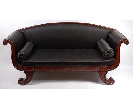 A George IV mahogany scroll end three-seater sofa, having black rexine upholstery with cushion seat and pair of end rolled cu