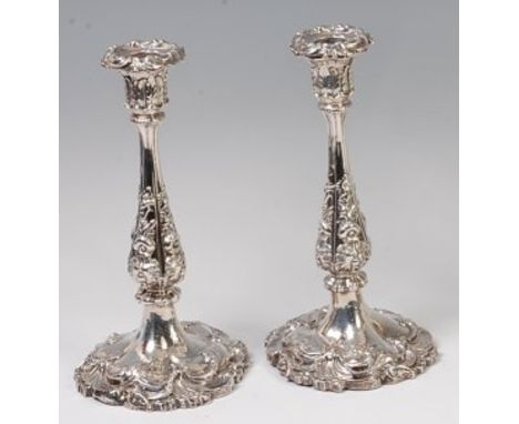 A pair of early Victorian silver Rococo Revival candlesticks, each having chased and embossed floral decoration, on loaded ba