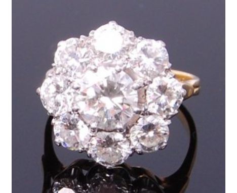 An 18ct gold diamond flower head cluster ring, arranged as a centre claw set brilliant weighing approx 1.1ct, in a surround o