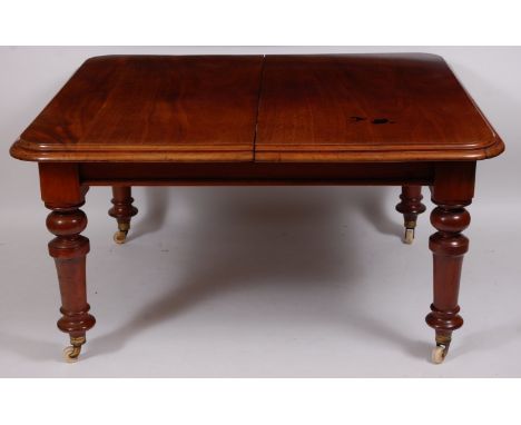 A Victorian mahogany extending dining table, the rectangular top with moulded edge and wind-out action, raised on turned supp