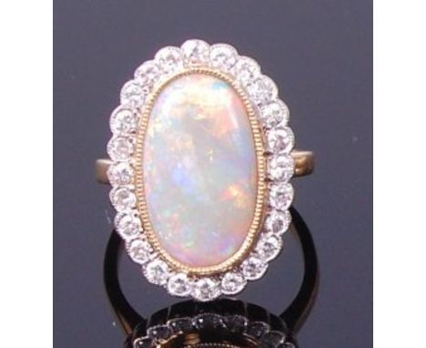 An 18ct gold, opal and diamond ring, arranged as a large cabochon opal measuring approx 18 x 11mm, within a surround of small