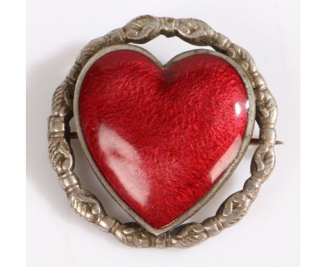 A red enamel brooch in the form of a heart, the border depicting clasped hands, set on unmarked white metal, 3cm diameter