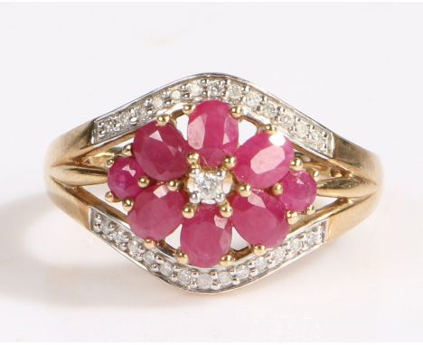 A modern 9 carat gold ruby and diamond cluster ring, the flowerhead comprised of six oval cut rubies with a round cut ruby to