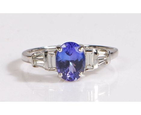 18 carat white gold and Tanzanite ring, the central oval cut tanzanite weighing 1.25 carats is elegantly accented by one bagu