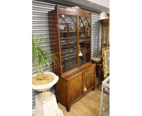 A Regency mahogany bookcase, circa 1820, set back upper section with Gothic arched astragal glazed twin doors opening to adju