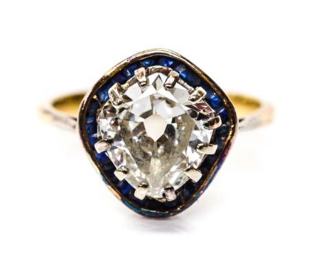 A diamond solitaire ring with blue sapphire border surround, the kite shaped old cut diamond weighing approximately 1.50 cara