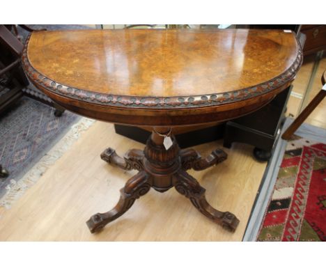 A mid Victorian burr walnut and strung demi-lune pedestal games table, circa 1860, fold-over revolving top, green baize lined