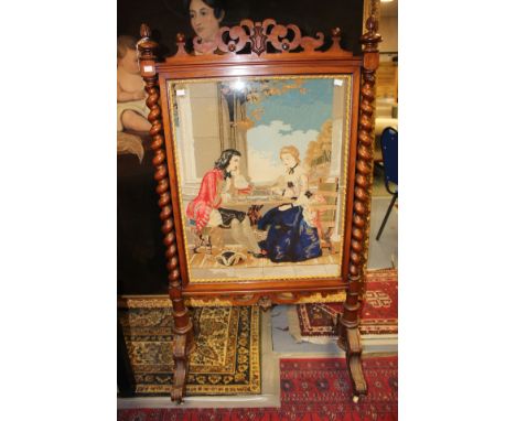 A late Victorian walnut firescreen, with barley twist uprights, the centre inset with a woolwork panel depicting a couple pla
