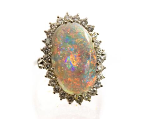 An 18ct white gold opal and diamond dress ring, claw set cabochon black opal, approximately 20mm by 12mm, displaying orange, 