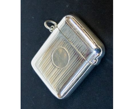 An Edwardian silver vesta case, engine turned with striated decoration, the front with vacant circular cartouche, gilt interi