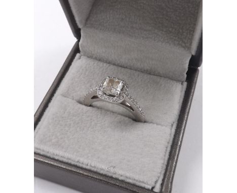 Platinum cushion-cut solitaire diamond ring, in a round brilliant-cut diamond surround with set shoulders, the centre stone e