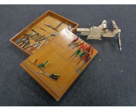 A mid 20th century wall mounted tool cabinet with key containing hand tools and a vintage metal bench vice 