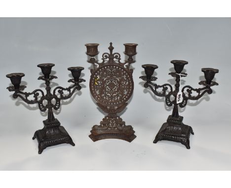 A GROUP OF THREE CAST IRON NINTEENTH CENTURY CANDELABRA comprising a cast iron double candlestick with a circular central pan
