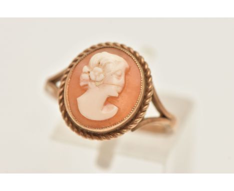 A 9CT GOLD CAMEO RING, of an oval form, carved shell cameo depicting a lady in profile, milgrain collet set within a fine rop