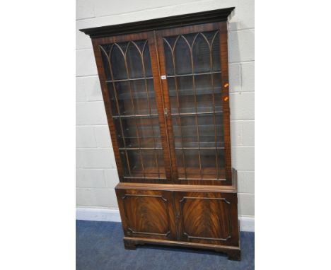 A REPRODUCTION MAHOGANY BOOKCASE, with double glazed doors, that are enclosing five glass shelves, over double cupboard doors
