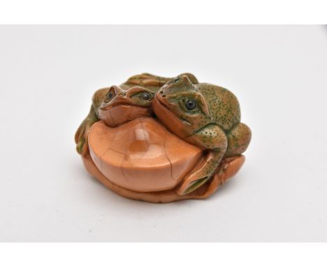 A NETSUKE, carved vegetable ivory depicting two frogs on a leaf, approximate length 45mm, signed to base, (condition report: 